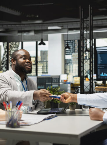 Black woman new hire receiving access key card and employee ID from the HR team Black woman new hire receiving access key card and employee ID from the HR team, completing employment and registration for the onboarding process. Workplace identification badge.