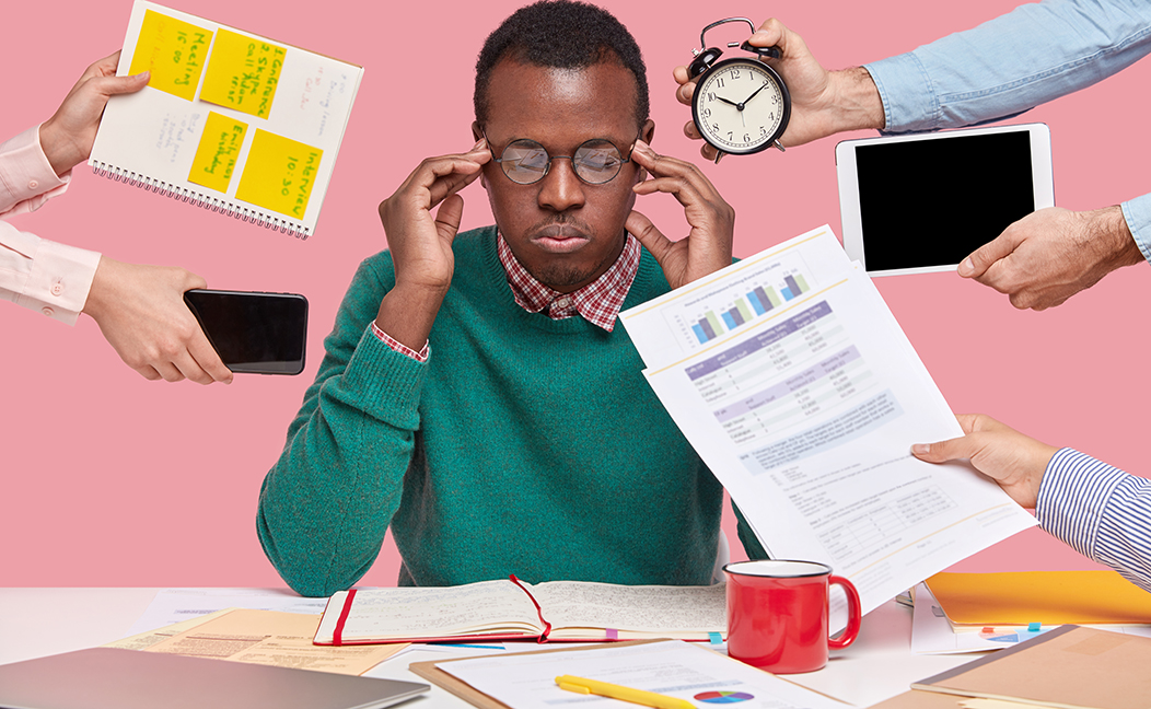 African american man sitting desk surrounded with gadgets papers 1